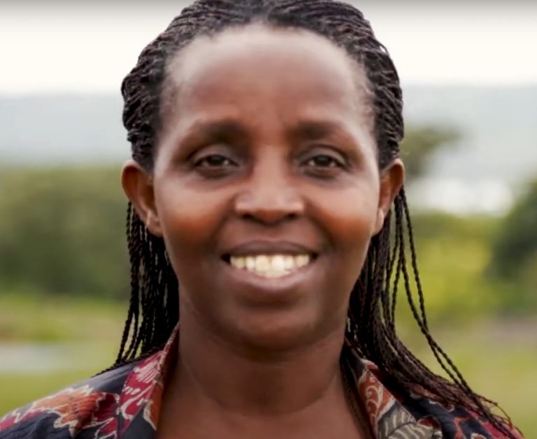 Marie Laetitia Kayitesire ler med sina kaffeodlingar som bakgrund