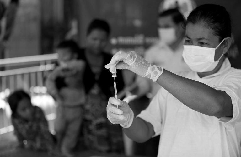 Kvinna som håller i en spruta med covid-19-vaccin i Kambodja.